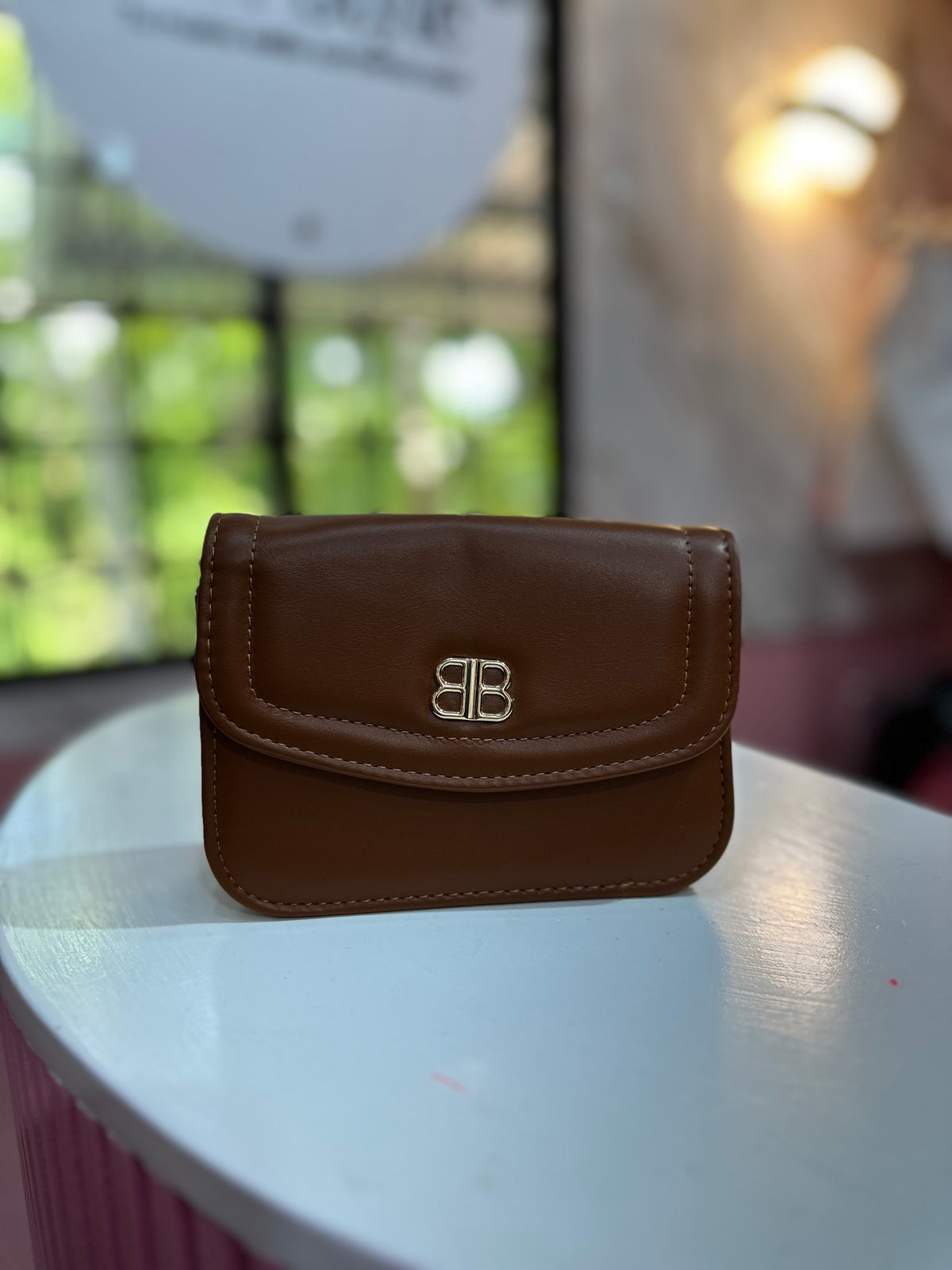 Mini cartera en color café con textura lisa y correa ajustable