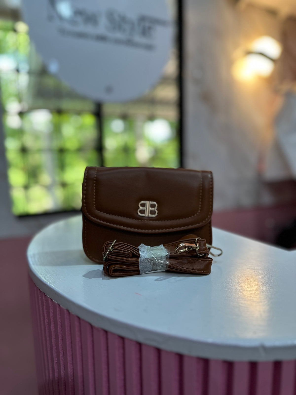Mini cartera en color café con textura lisa y correa ajustable