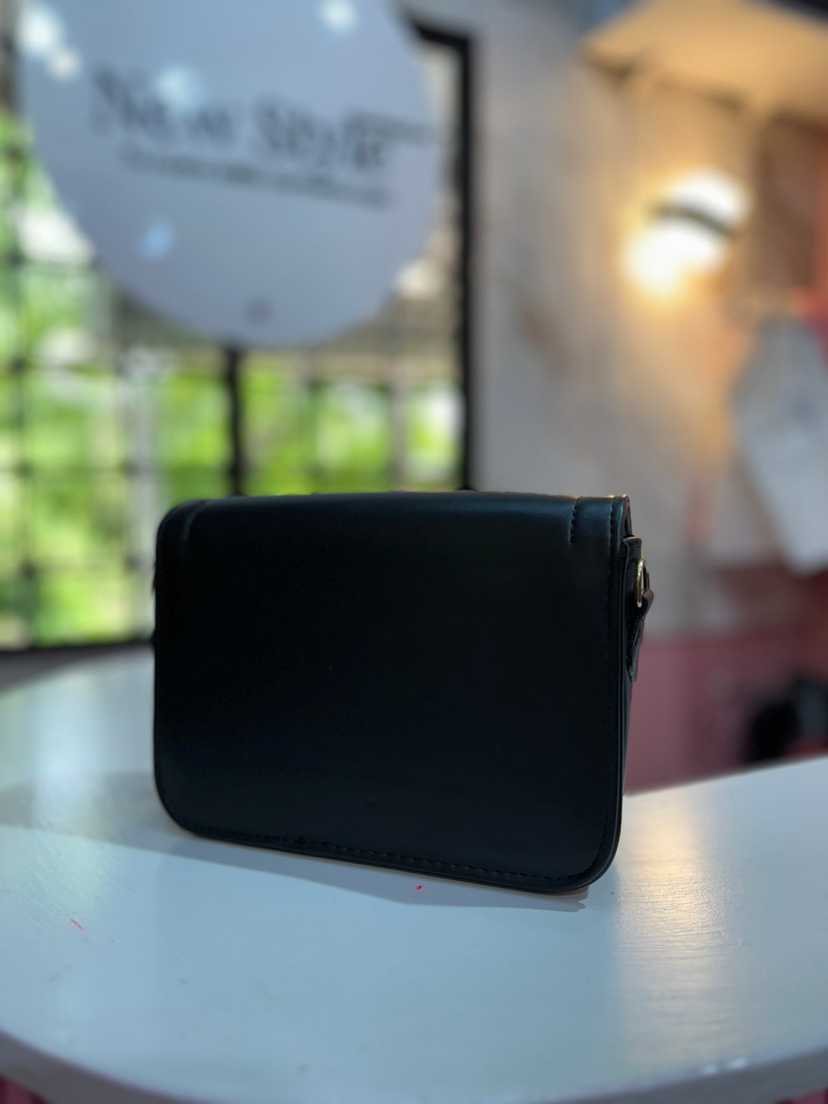 Cartera de color negro con textura lisa y correa ajustable a juego