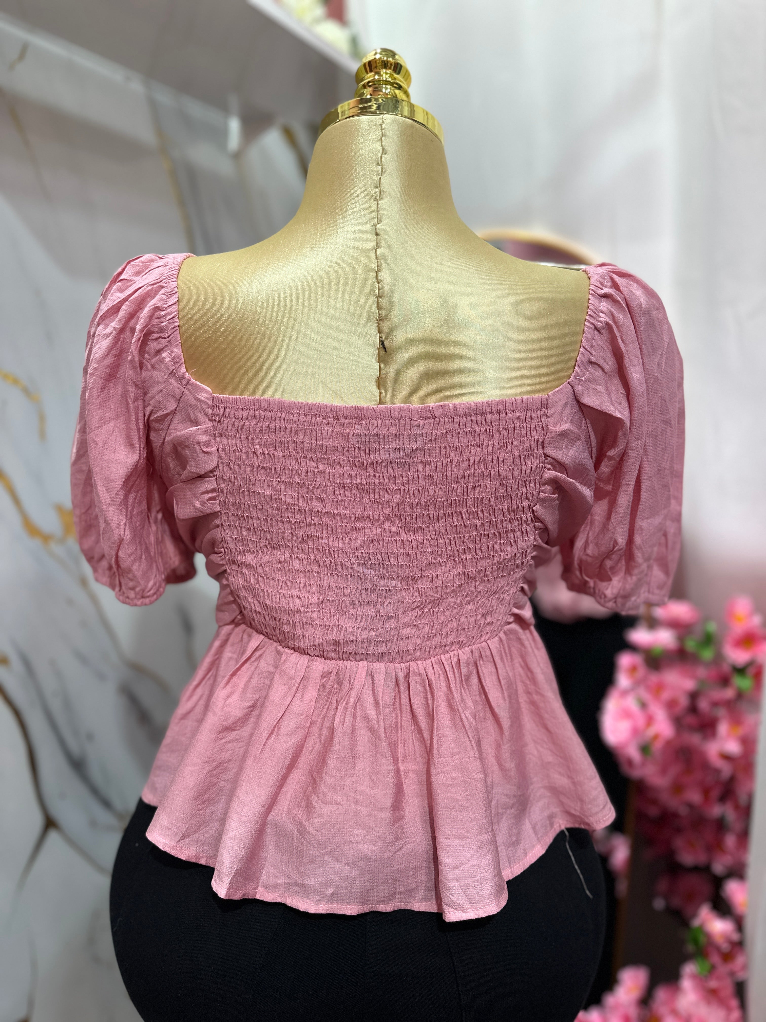 Blusa rosada con mangas abullonadas con diseño fruncido en el frente