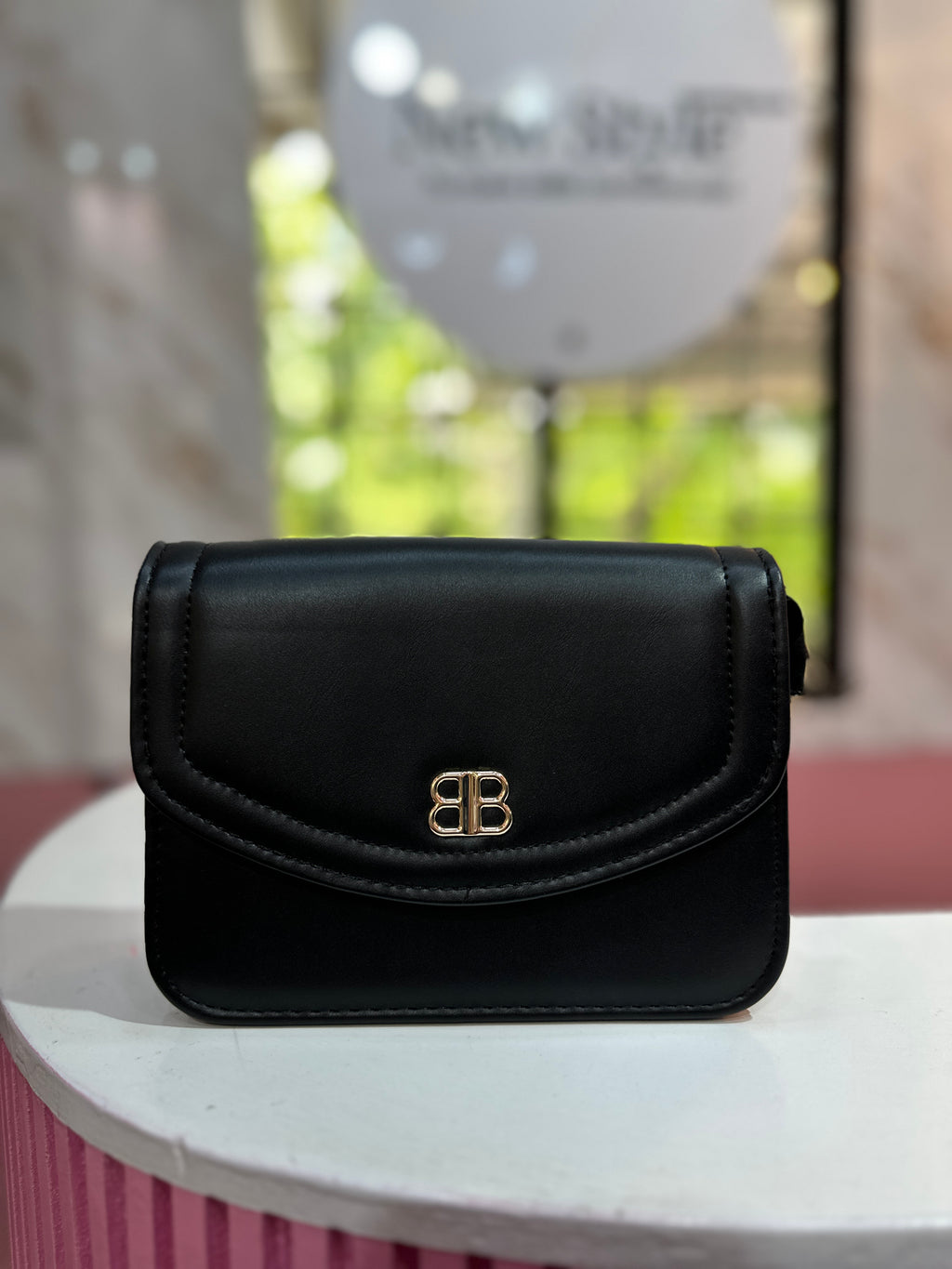 Cartera de color negro con textura lisa y correa ajustable a juego