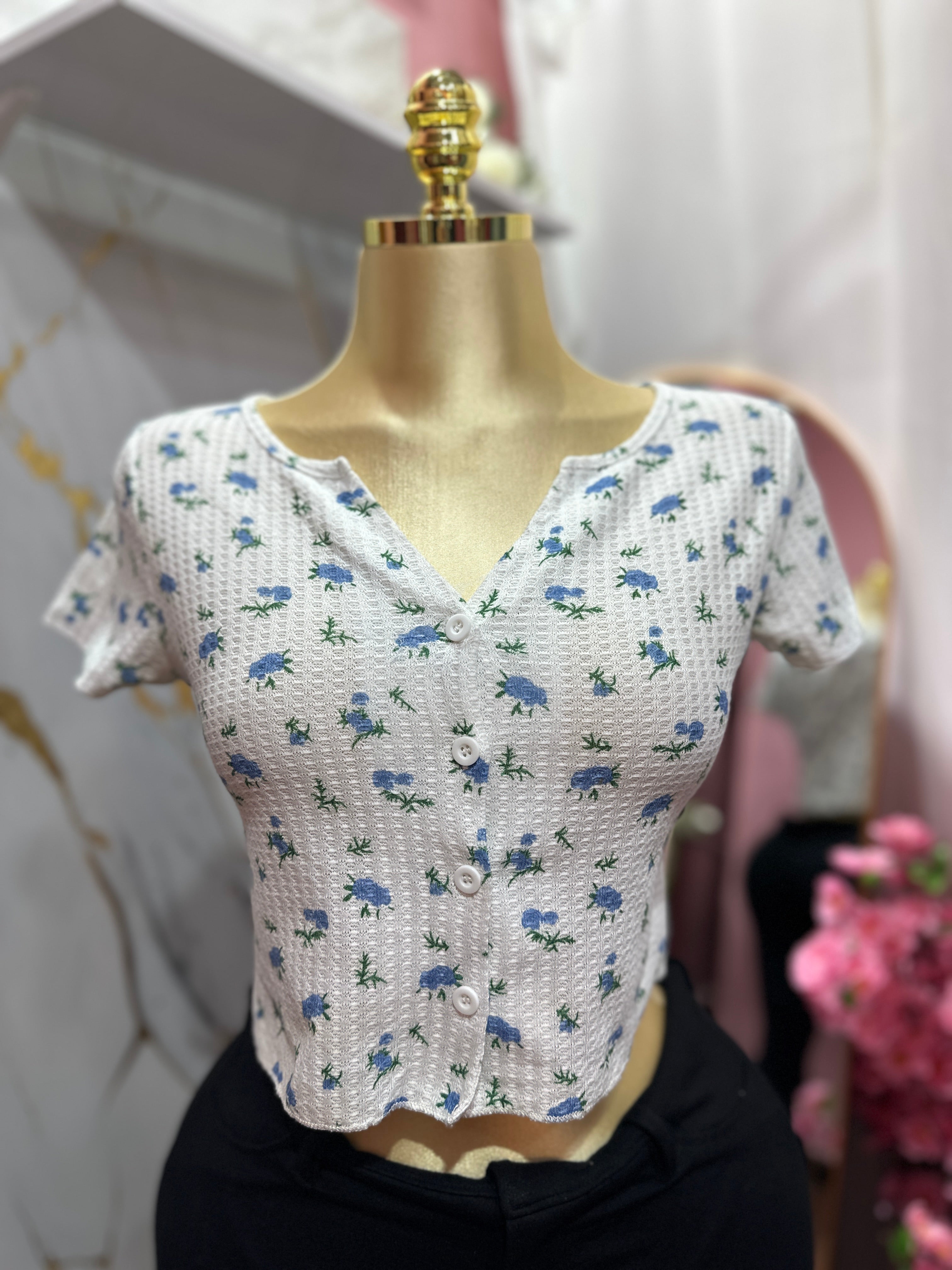 Crop top blanco con estampado floral azul y diseño de botones enfrente