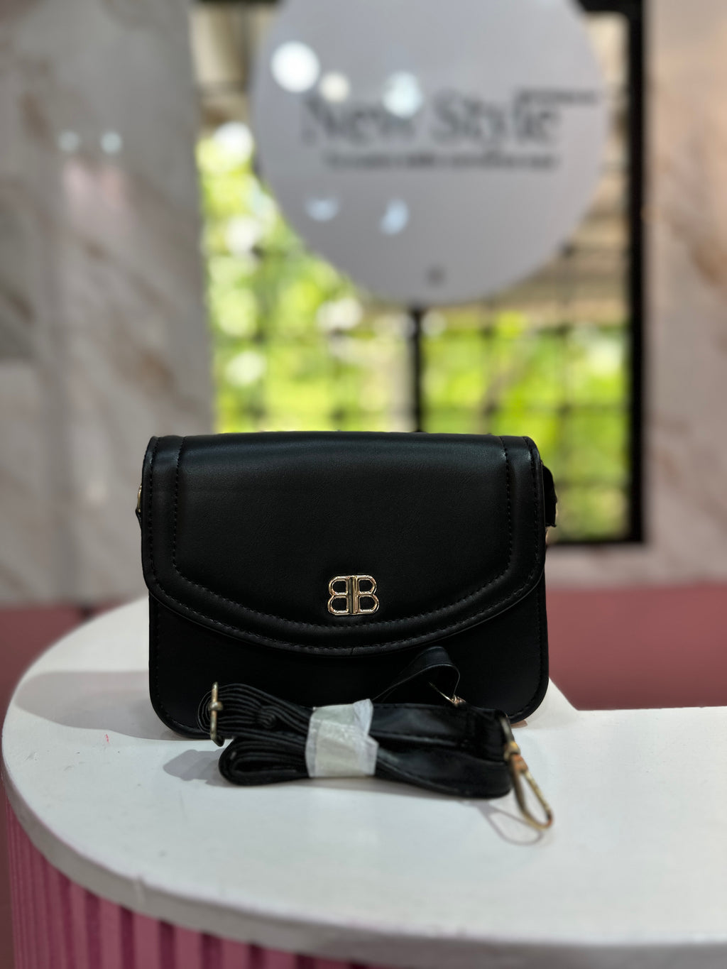 Cartera de color negro con textura lisa y correa ajustable a juego