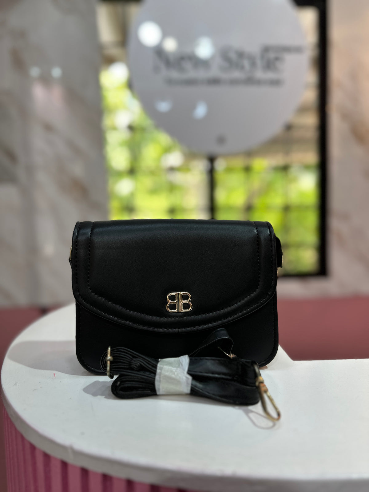 Cartera de color negro con textura lisa y correa ajustable a juego