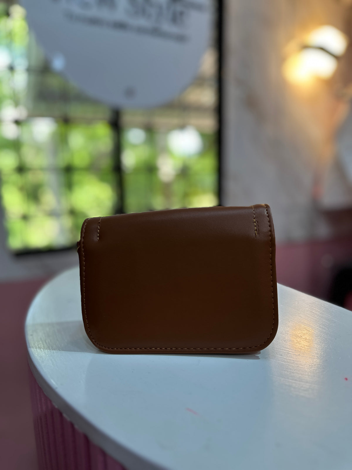 Mini cartera en color café con textura lisa y correa ajustable