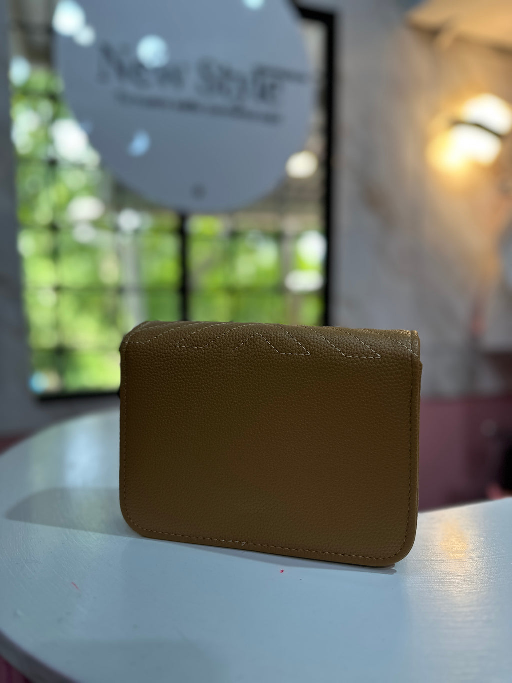 Cartera de color café con textura acolchada y correa ajustable a juego