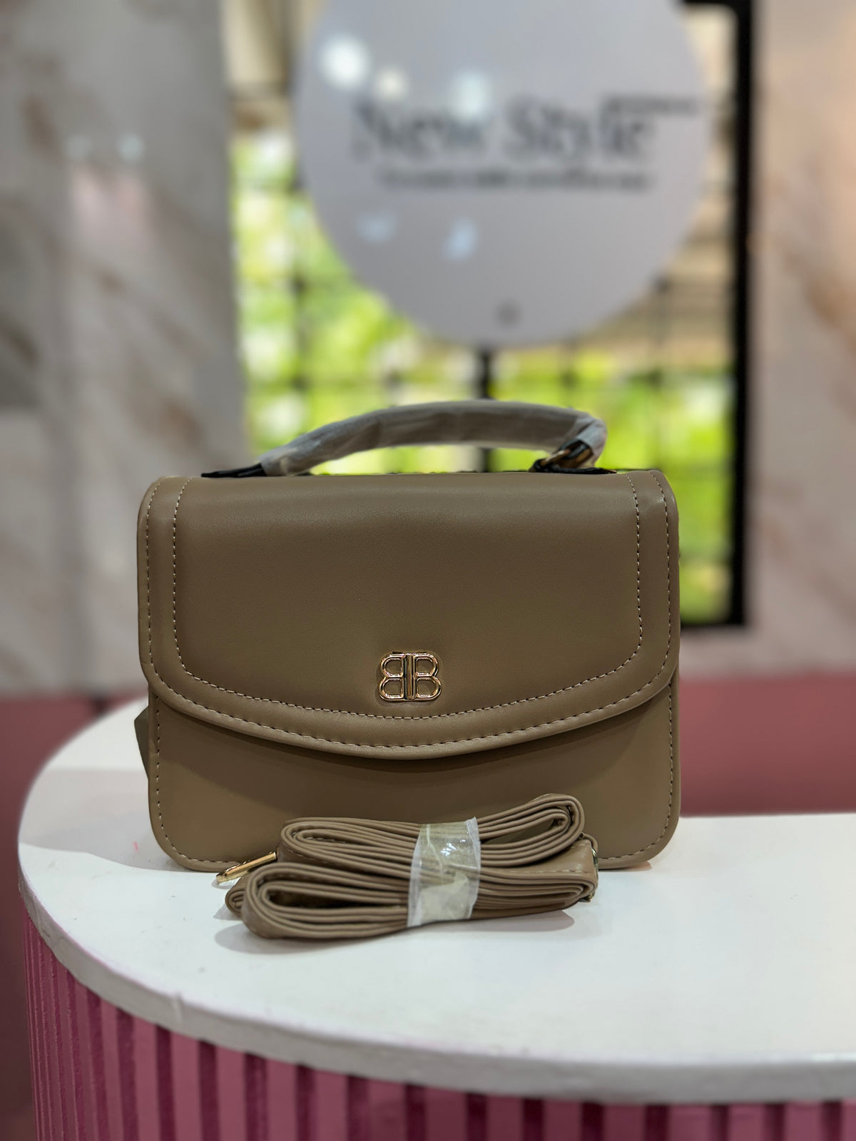 Cartera en tono beige con textura lisa y correa ajustable a juego