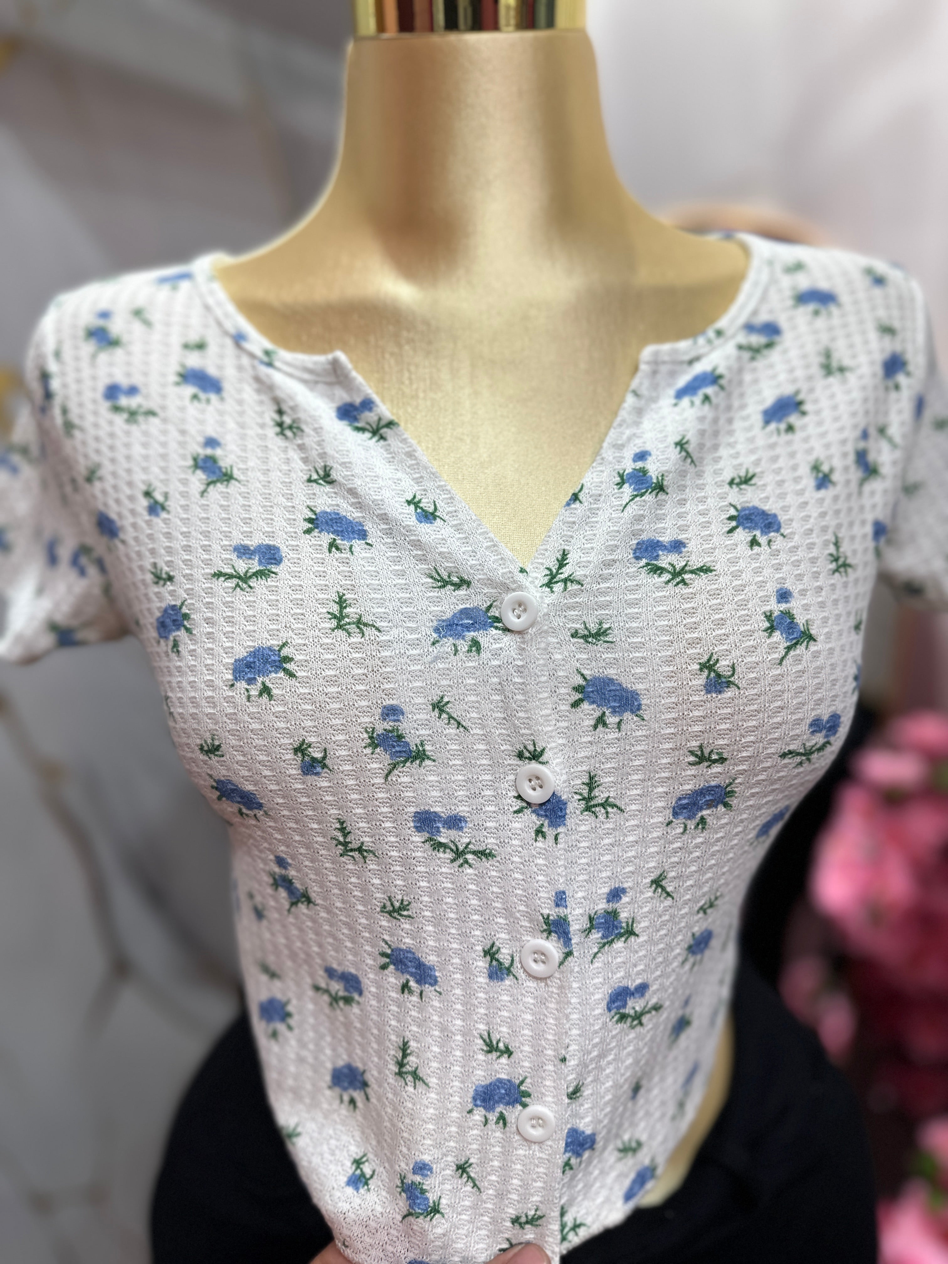Crop top blanco con estampado floral azul y diseño de botones enfrente