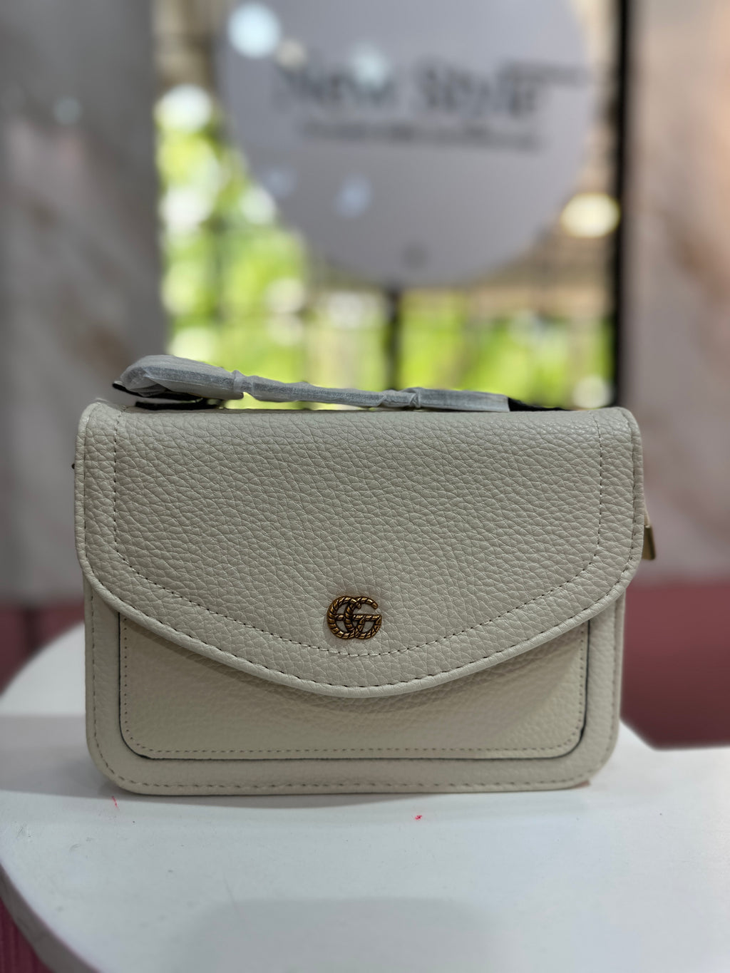 Cartera de color crema con textura granulada y con correa ajustable
