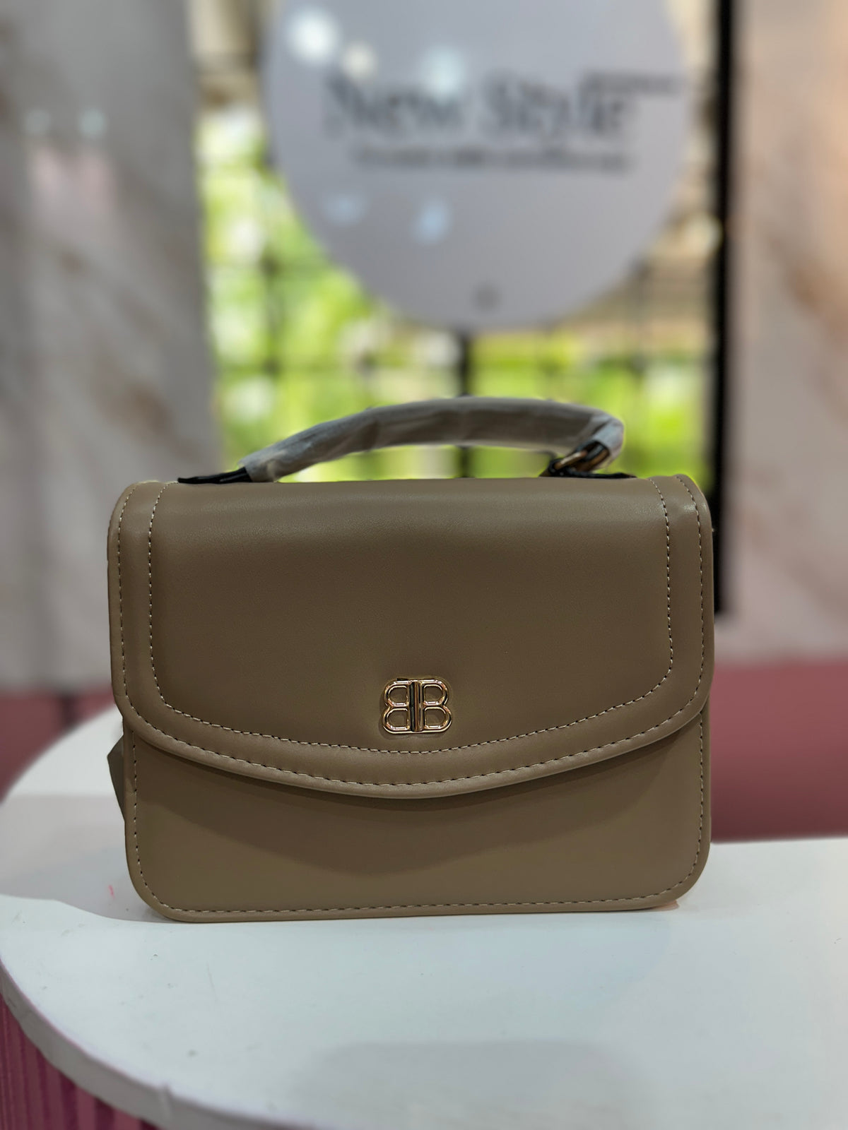 Cartera en tono beige con textura lisa y correa ajustable a juego