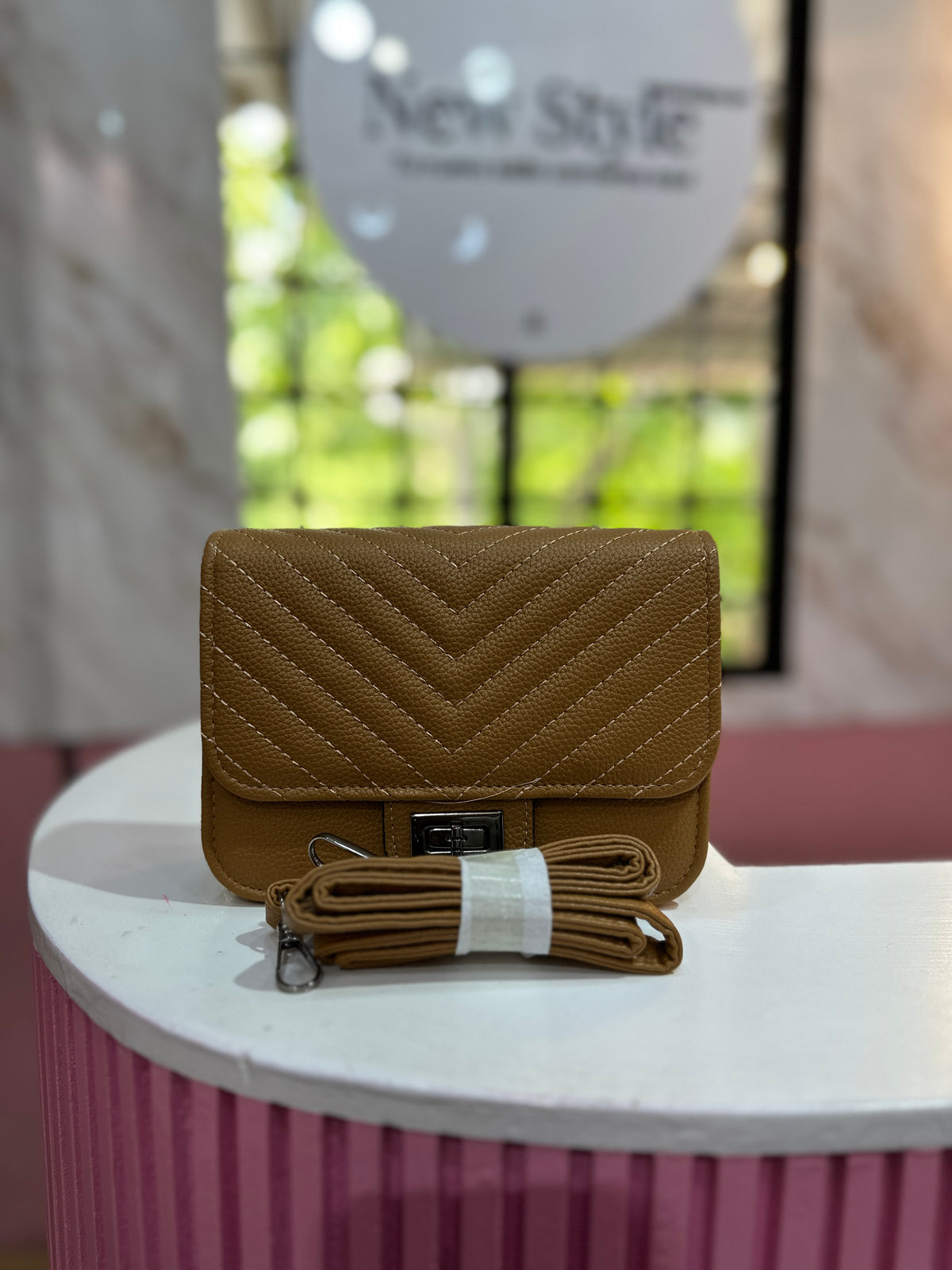 Cartera de color café con textura acolchada y correa ajustable a juego