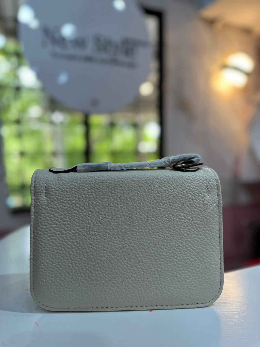 Cartera de color crema con textura granulada y con correa ajustable