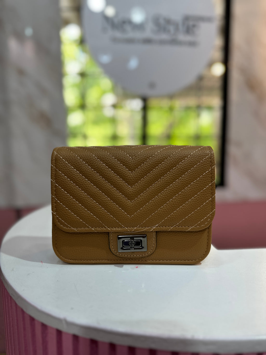 Cartera de color café con textura acolchada y correa ajustable a juego