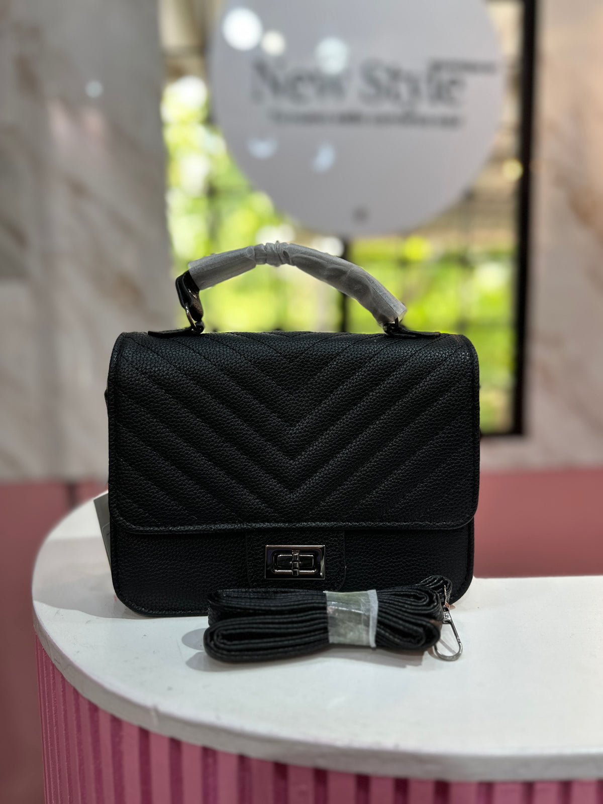 Cartera en color negro con diseño acolchado y correa ajustable a juego