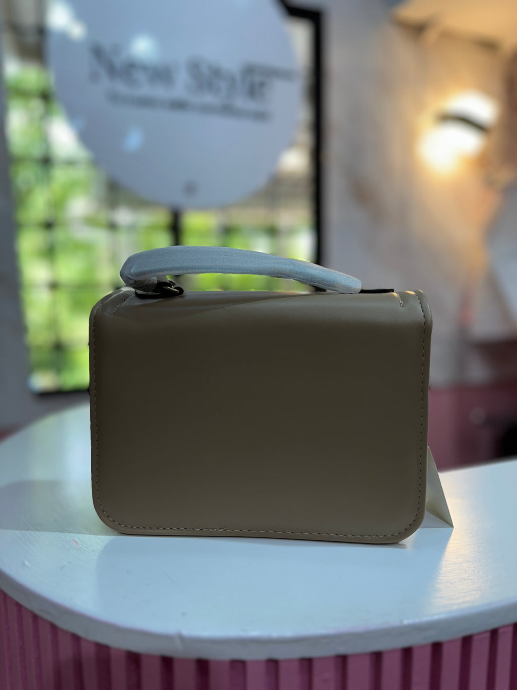 Cartera en tono beige con textura lisa y correa ajustable a juego